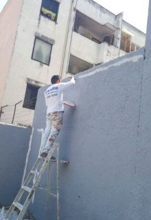 pintor de casas pintando la pared de un patio de color gris