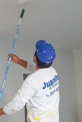 pintor de casas pintando con rodillo y pintura blanca el techo de una cocina