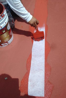 pintor de casas impermeabilizando una azotea con una brocha gruesa